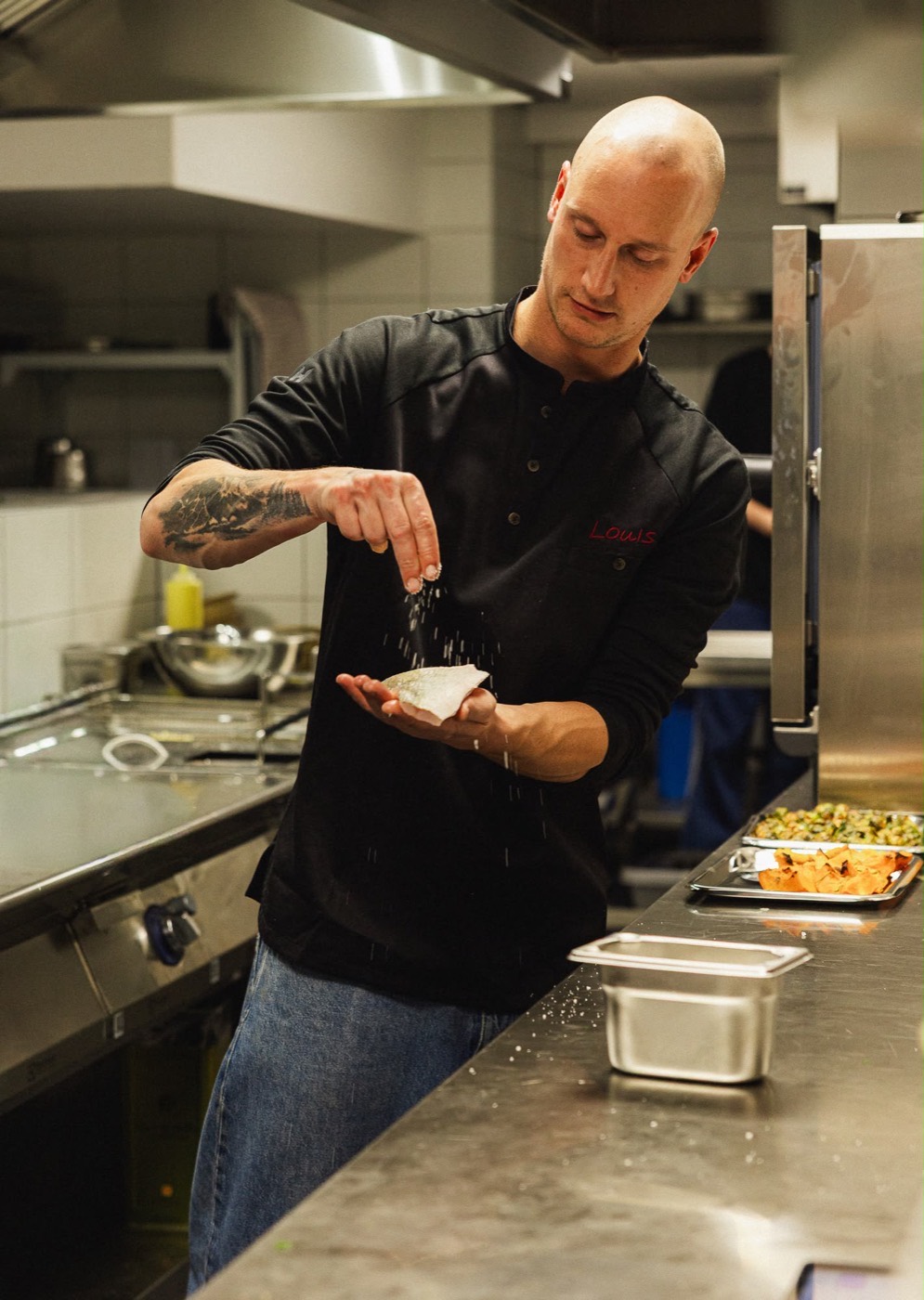 De chef kruidt een gerecht in de keuken van Louis