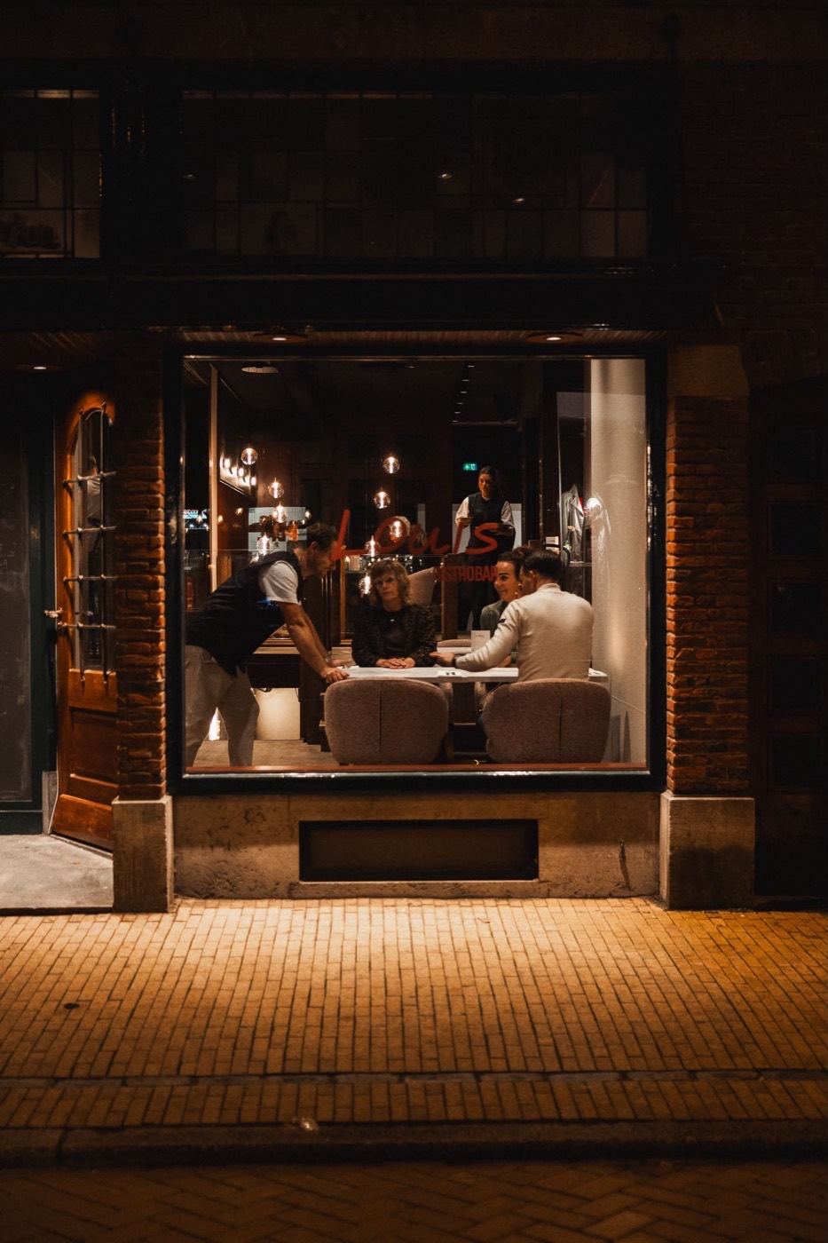 De voorkant van Louis ’s avonds, met zicht door het raam naar binnen